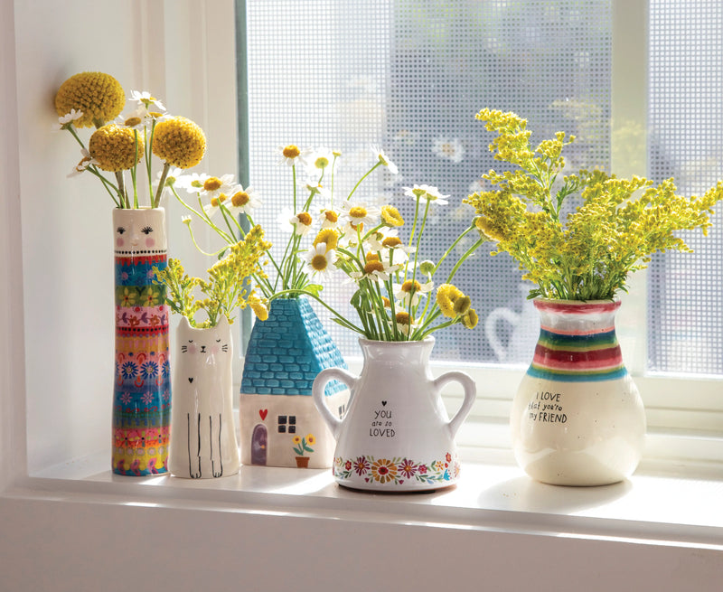 Different bud vases sitting on a window sill.