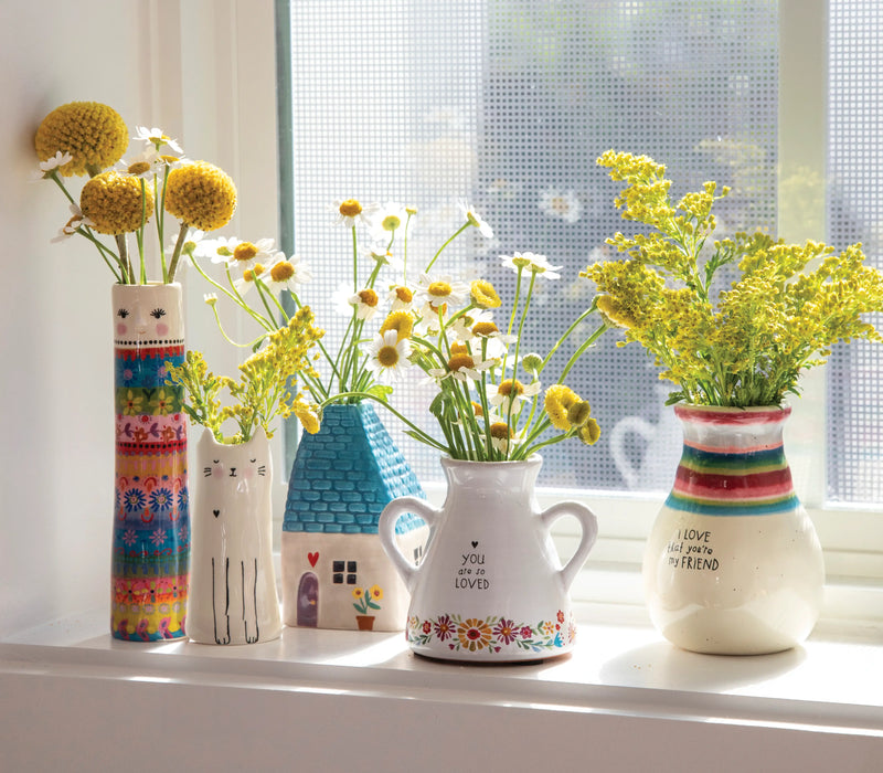 Different bud vases sitting on a window sill.